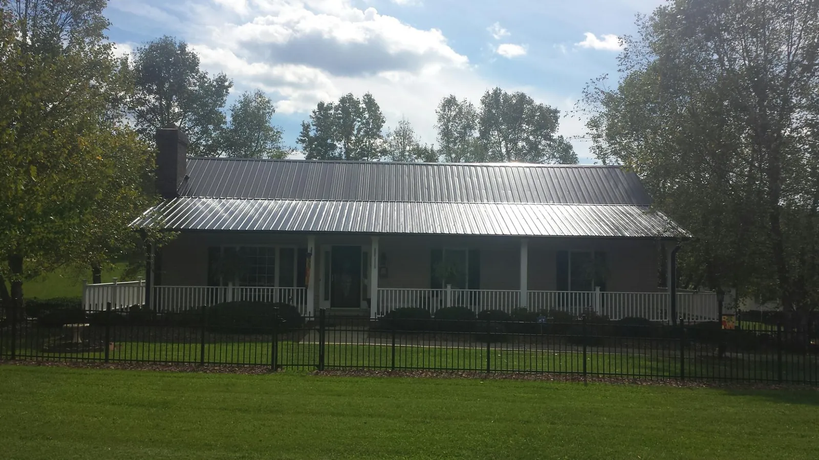 Gray metal roof on a brick ranch with a full width front porch — Gutter Guard Installation work by our crew in Harvey